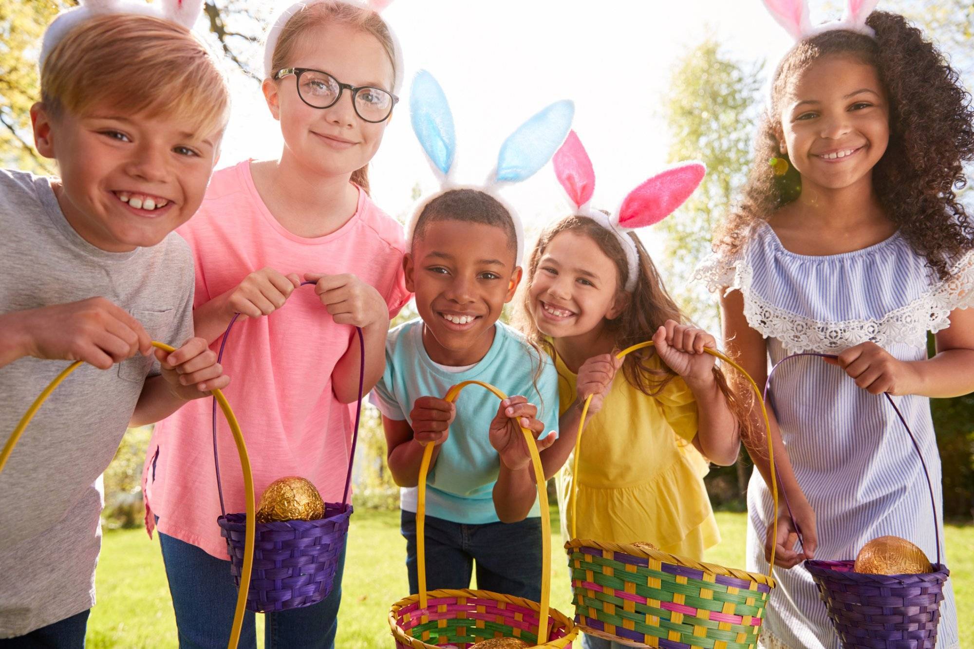 Portrait Of Five Children Wearing Bunny Ears On Easter Egg Hunt In Garden