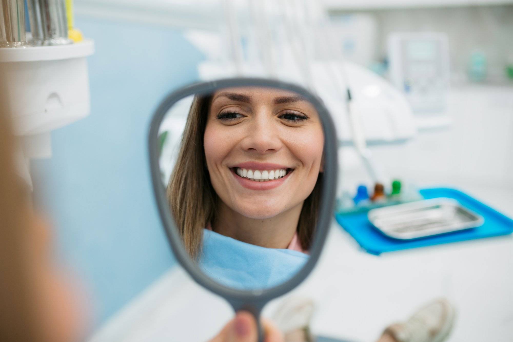 A happy woman looking herself in the hand held mirror