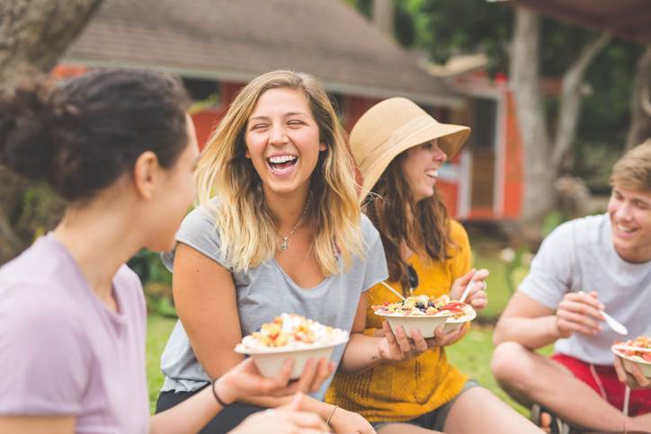 Friends eating smoothie bowls topped with fresh tropical fruit