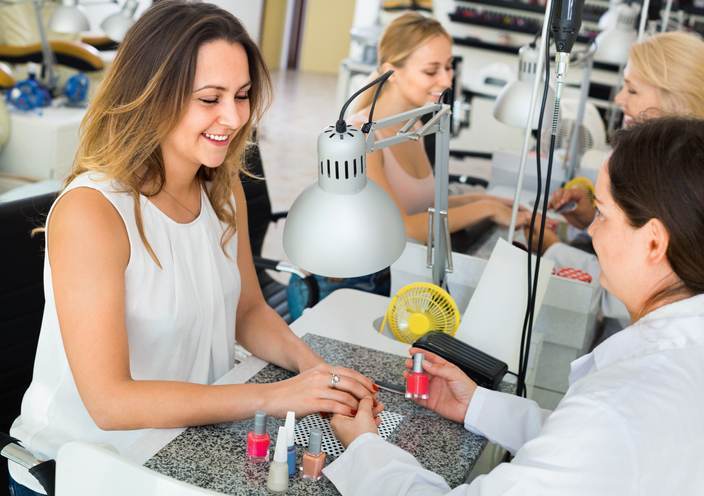 Two women clients having manicure done in nail salon